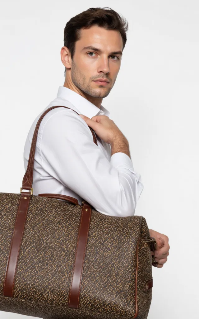 A French male model with a Tweed travel bag, wearing a shirt, against a white background, in a front   facing close   up